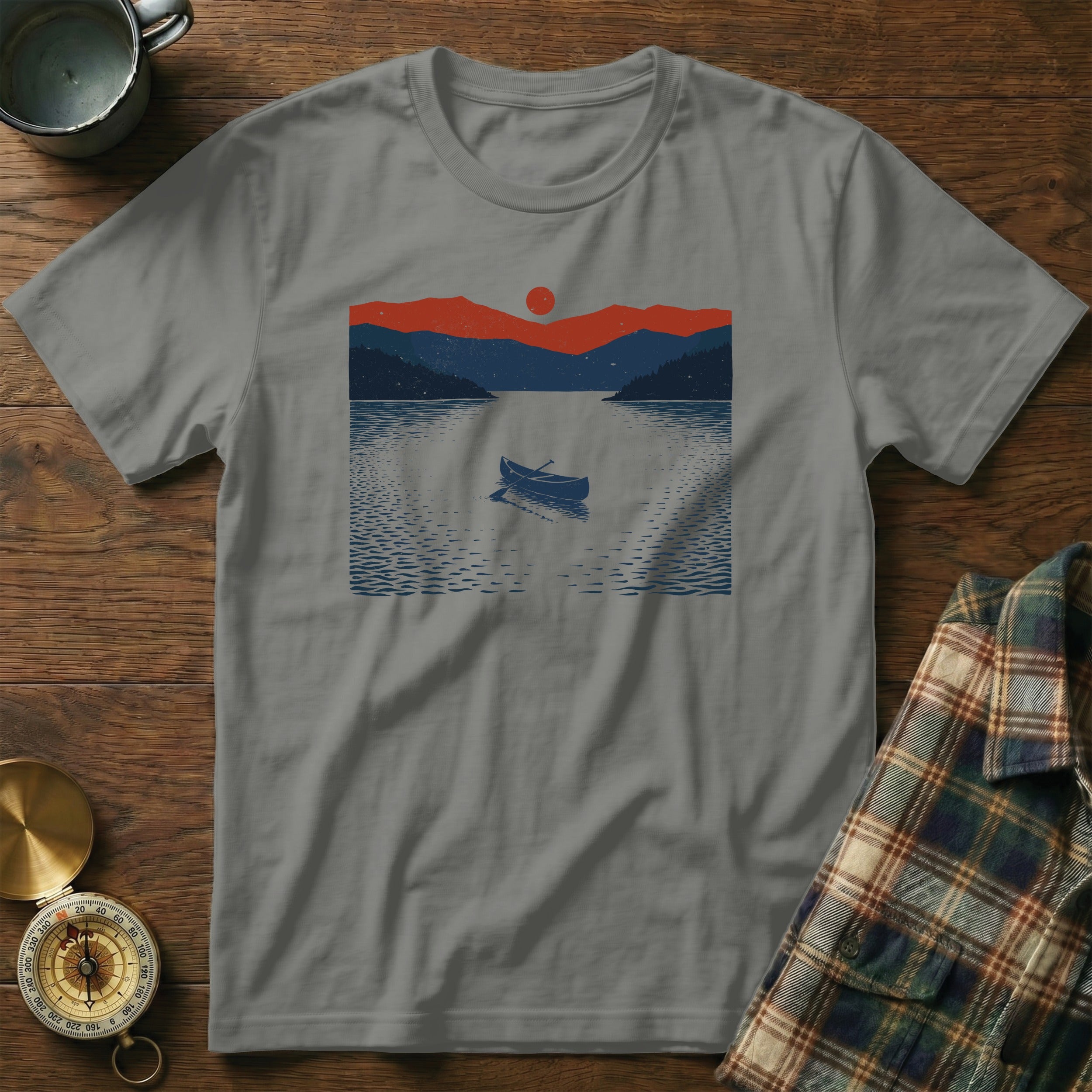 Grey t-shirt with a graphic of a canoe on a lake at sunset.