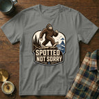 Bigfoot wearing sunglasses walking on a cliff with text "Spotted Not Sorry".