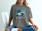 Grey t-shirt with a shield graphic of a palm tree, ocean, and text "Nowhere Near Done Exploring".