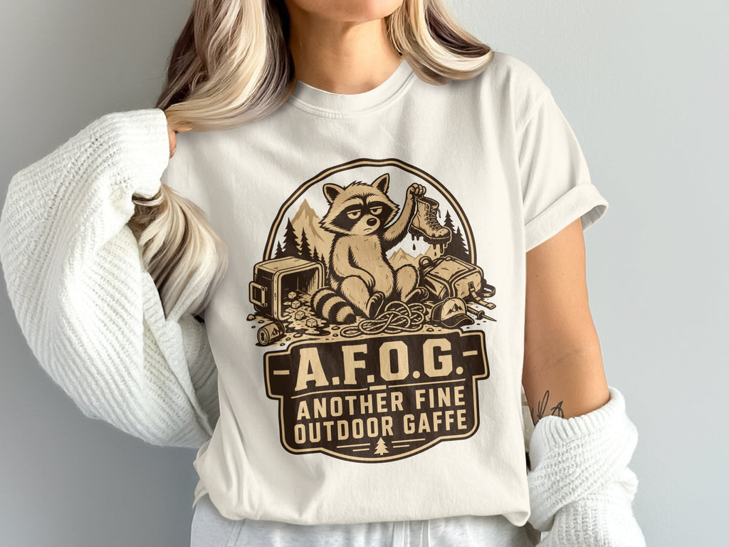T-shirt with raccoon holding a boot and text "A.F.O.G. Another Fine Outdoor Gaffe."
