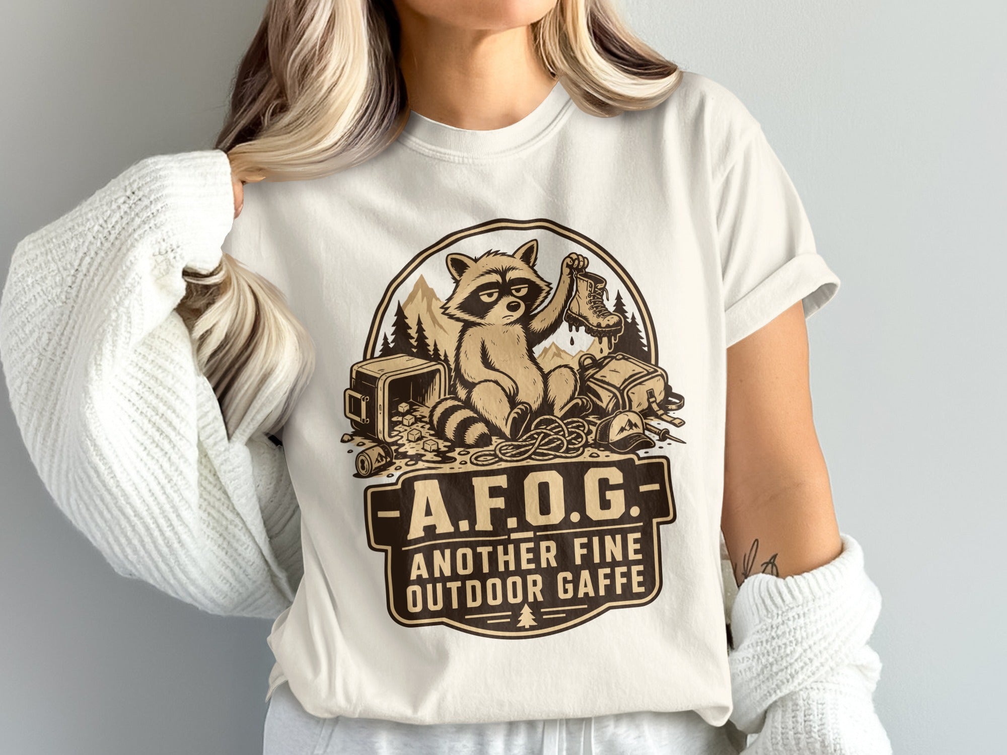 T-shirt with raccoon holding a boot and text "A.F.O.G. Another Fine Outdoor Gaffe."
