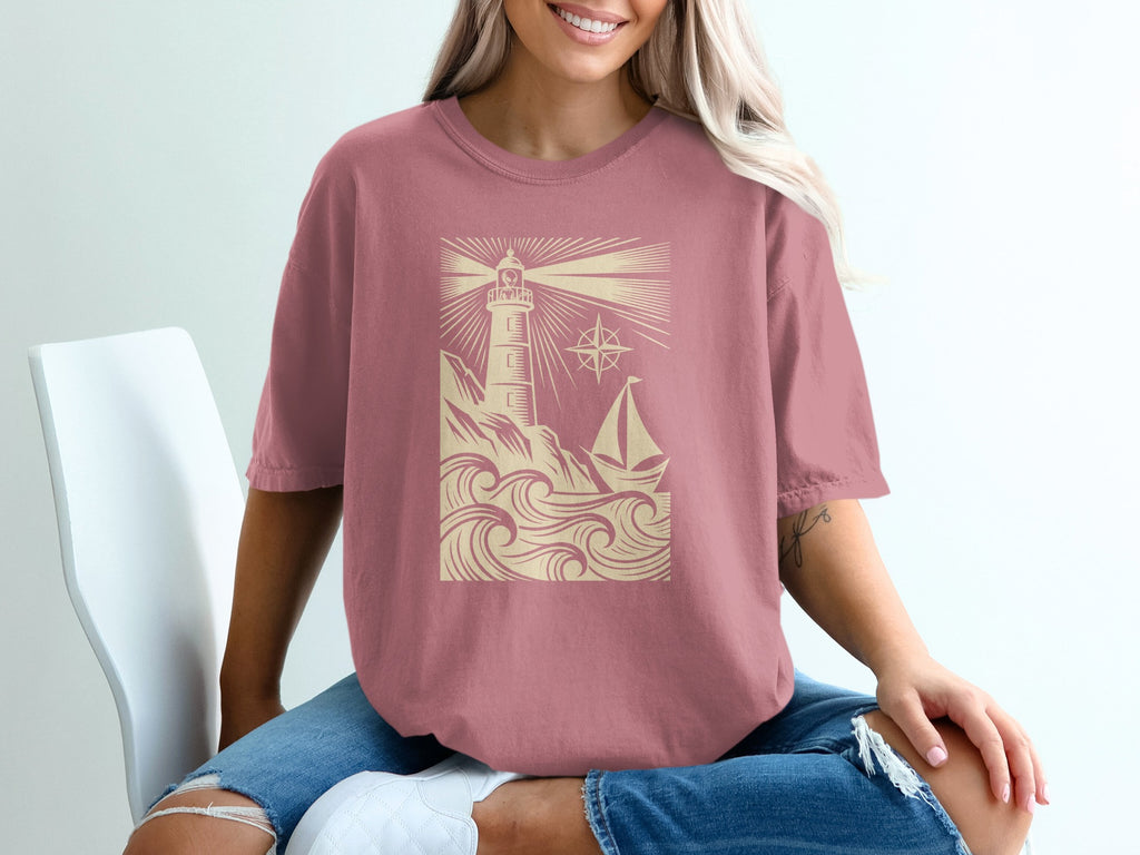 Pink t-shirt with lighthouse, sailboat, and compass design.