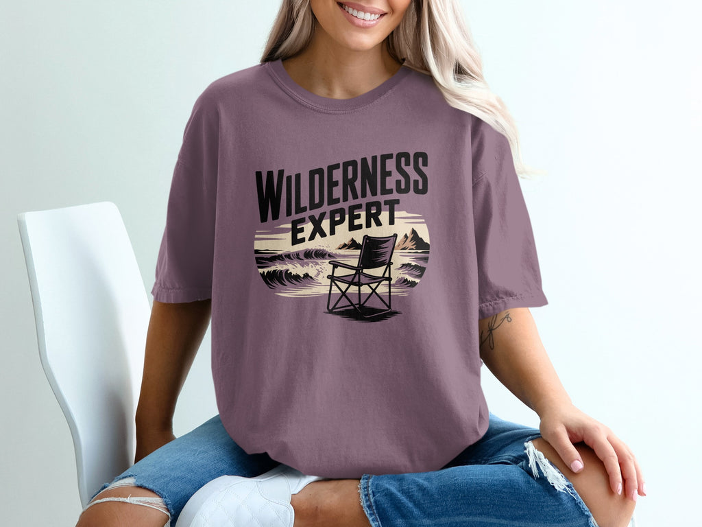 Purple t-shirt with "WILDERNESS EXPERT" text and beach scene graphic.