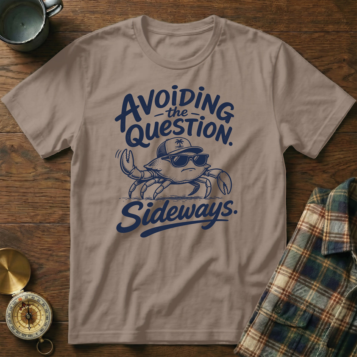 Brown t-shirt featuring blue text that reads Avoiding the Question Sideways and an illustration of a crab wearing sunglasses.