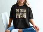 Black t-shirt with "THE OCEAN DOESN'T CARE EITHER" text.