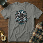 Grey t-shirt featuring a kraken and waves graphic with text "KRAKEN BEYOND THE DEPTHS".