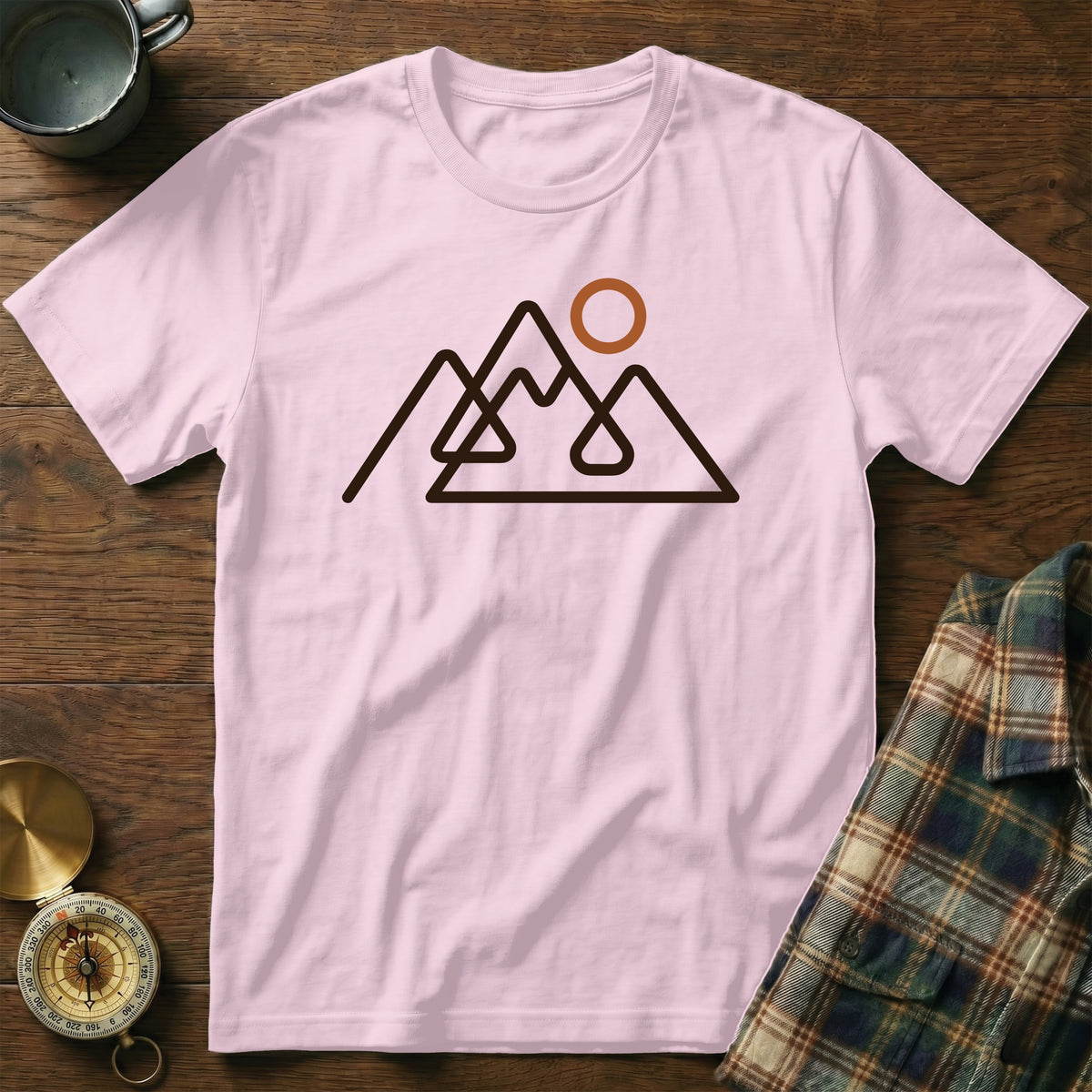 Pink t-shirt with a minimalist mountain range and sun graphic design.