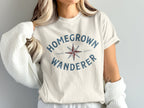 Cream t-shirt with "HOMEGROWN WANDERER" and compass graphic.