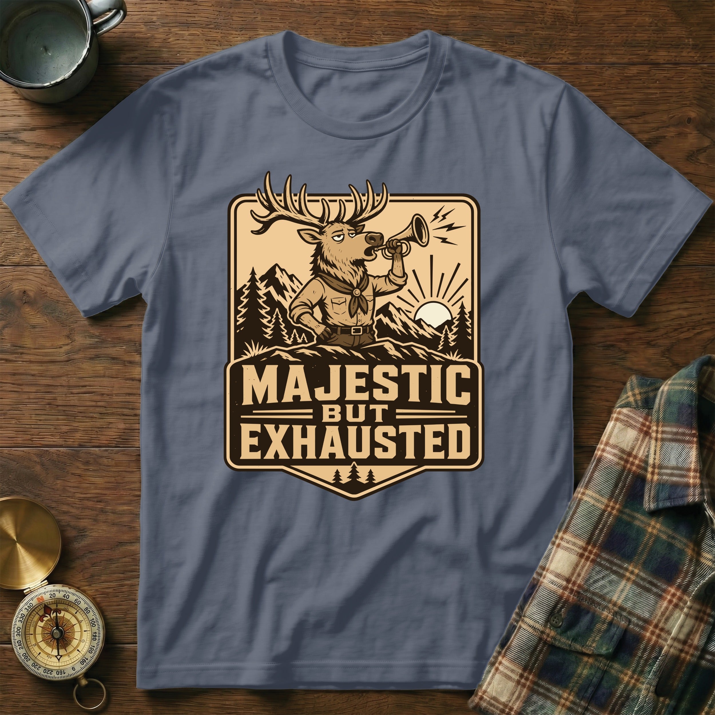 Deer blowing bugle with "Majestic But Exhausted" text, mountains, and sunrise on shirt.