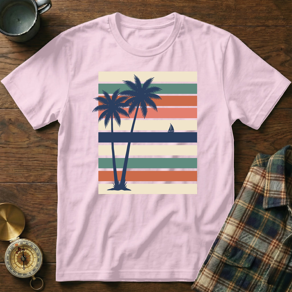 Pink t-shirt with two palm trees and a sailboat on striped background.