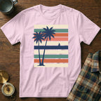 Pink t-shirt with two palm trees and a sailboat on striped background.