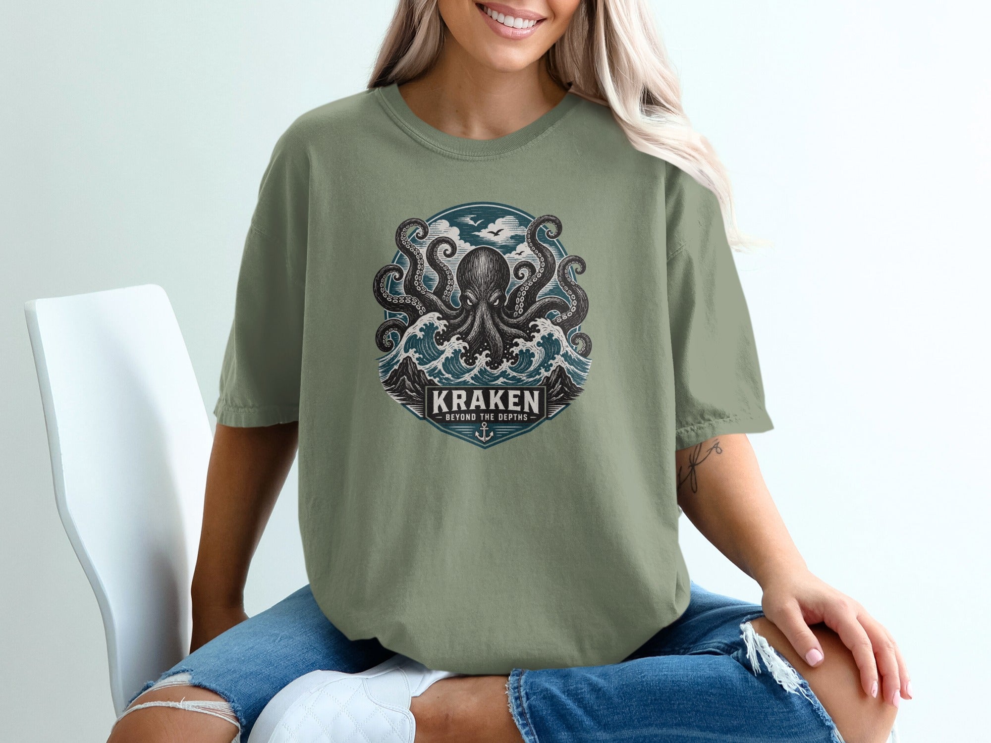 T-shirt with a kraken illustration, waves, birds, and text "Kraken Beyond the Depths".