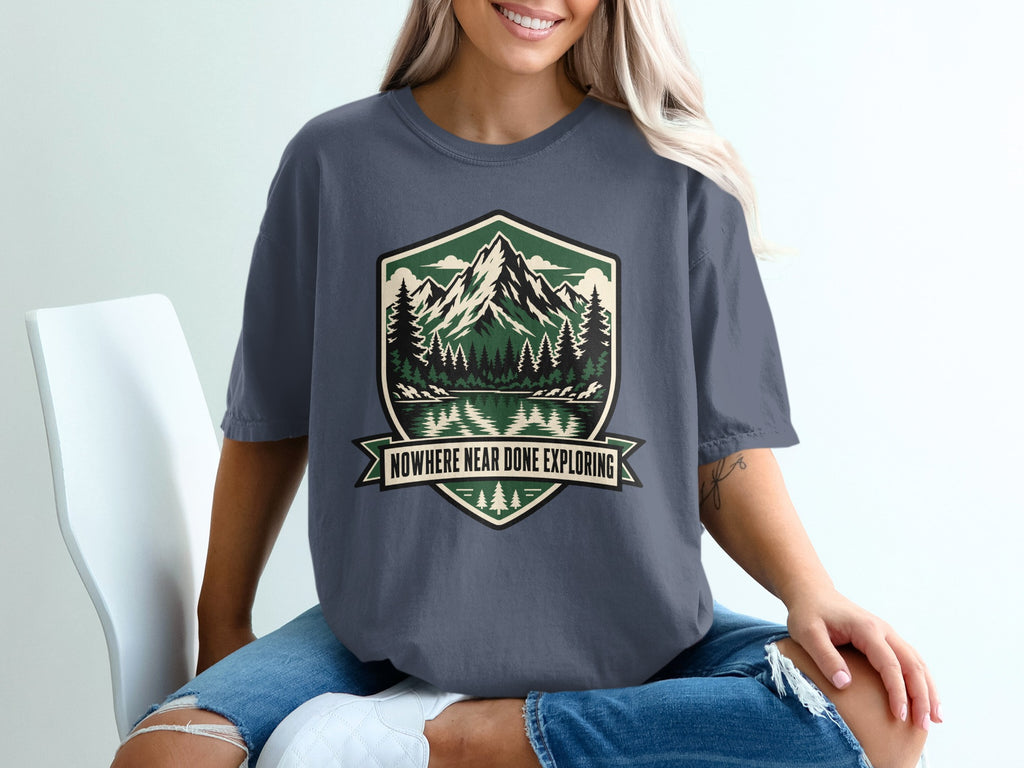 Dark gray t-shirt with shield logo featuring mountains, trees, reflection, and text.