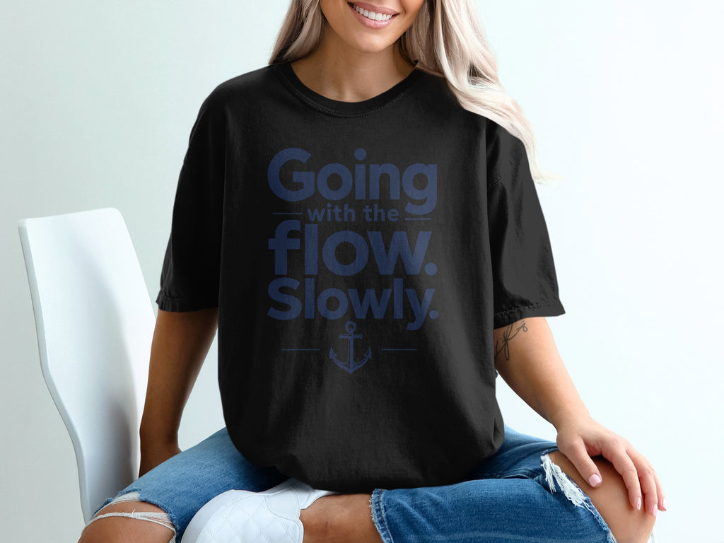A woman wearing a black t-shirt with blue text that reads Going with the flow. Slowly. and an anchor graphic.
