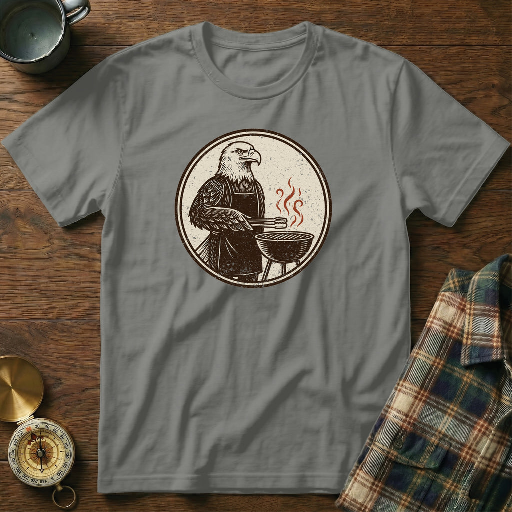 Grey t-shirt with graphic of eagle wearing apron grilling.