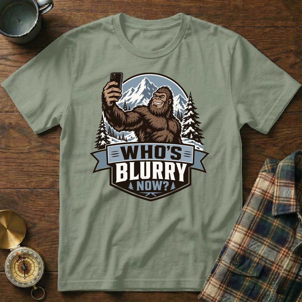 Bigfoot holding a smartphone in a snowy mountain landscape with the text "Who's Blurry Now?".