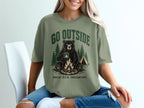 Green t-shirt with a graphic of a bear holding a mug by a campfire with "GO OUTSIDE" and "GREAT VIEW, UNCLEAR EXIT."