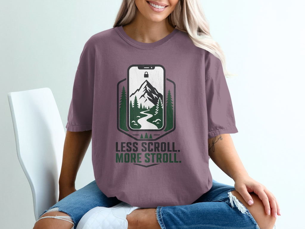 T-shirt with a phone graphic showing a mountain and trees, reading "Less Scroll. More Stroll."