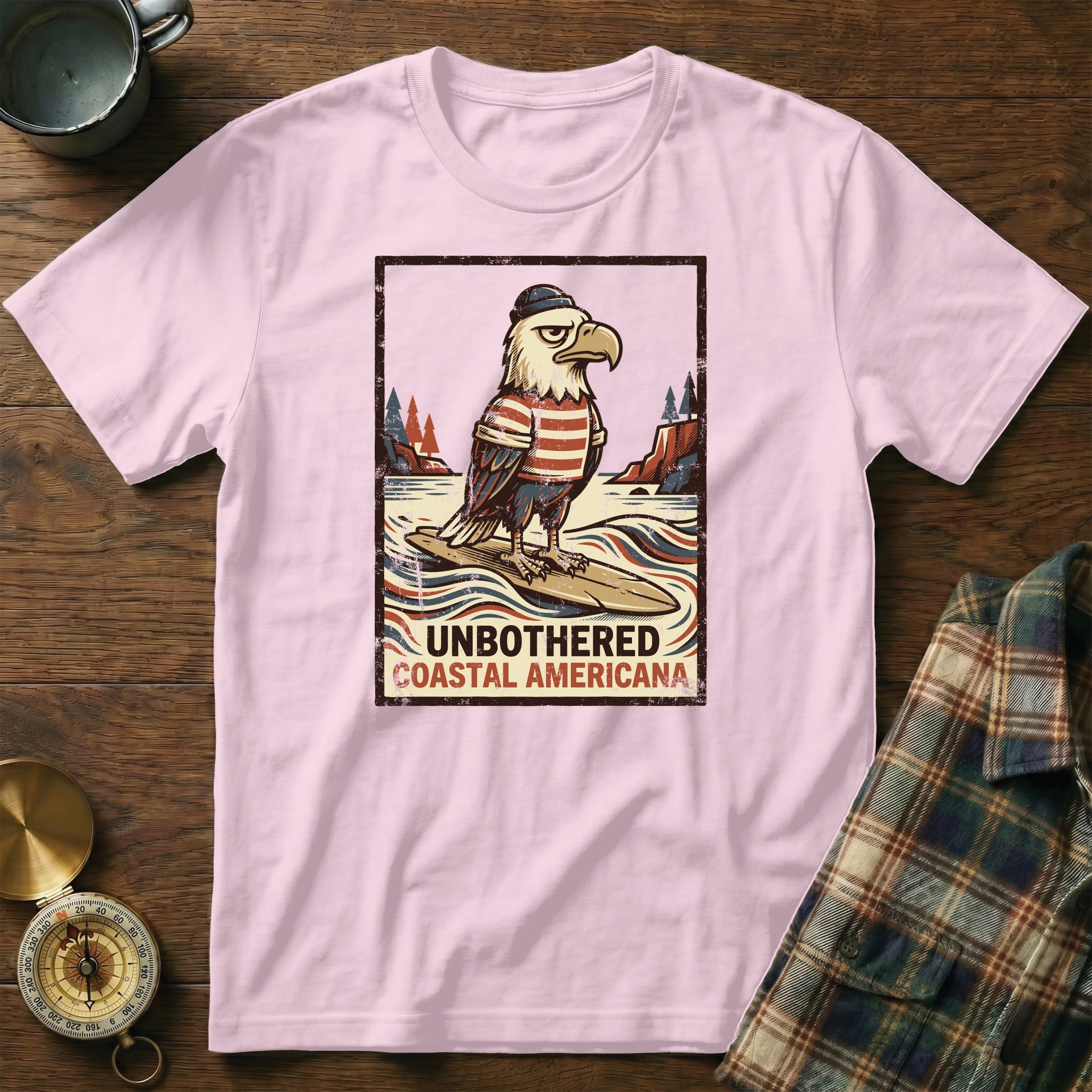 Eagle wearing a hat and striped shirt, surfing on a surfboard, with text "UNBOTHERED COASTAL AMERICANA".