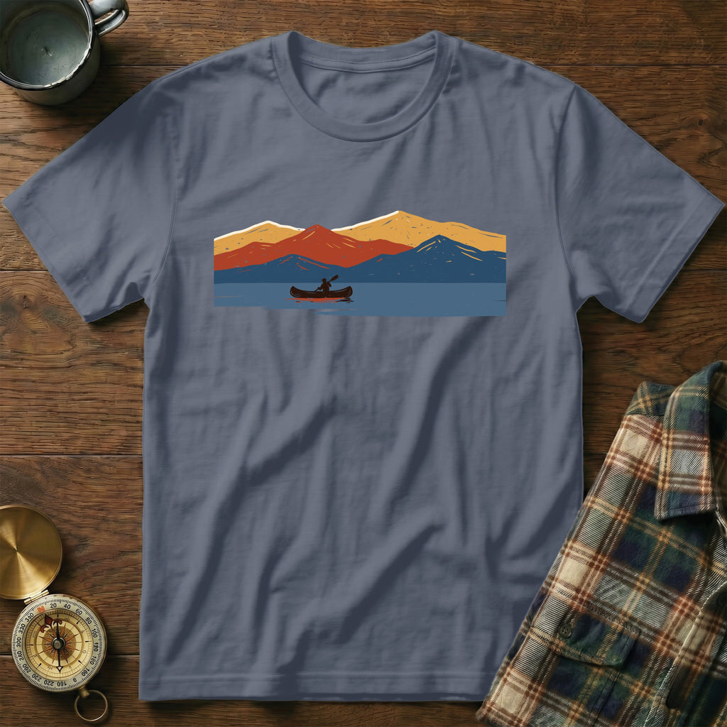 T-shirt with a graphic print of a person in a canoe on a lake with mountains.