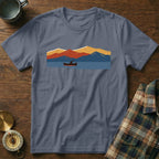 T-shirt with a graphic print of a person in a canoe on a lake with mountains.