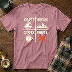 Pink t-shirt with text "Coast Mountains Coffee People" and icons of wave, mountain, coffee cup, and crossed out.