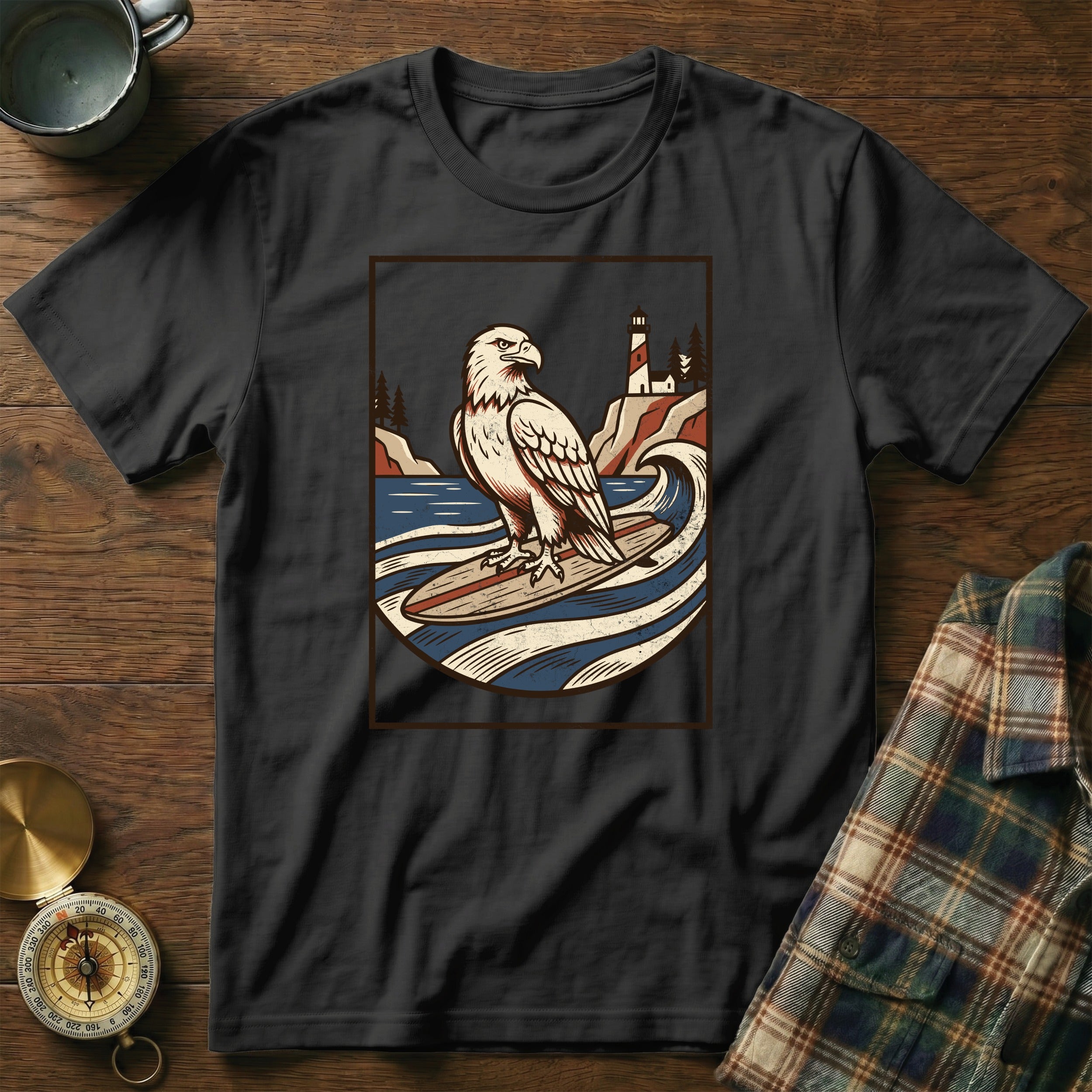 Black t-shirt with a graphic of an eagle surfing with a lighthouse in the background.