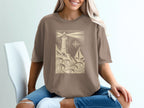 T-shirt with lighthouse and sailboat graphic on wavy water.