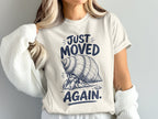Hermit crab graphic on a cream t-shirt with text "Just Moved Again".
