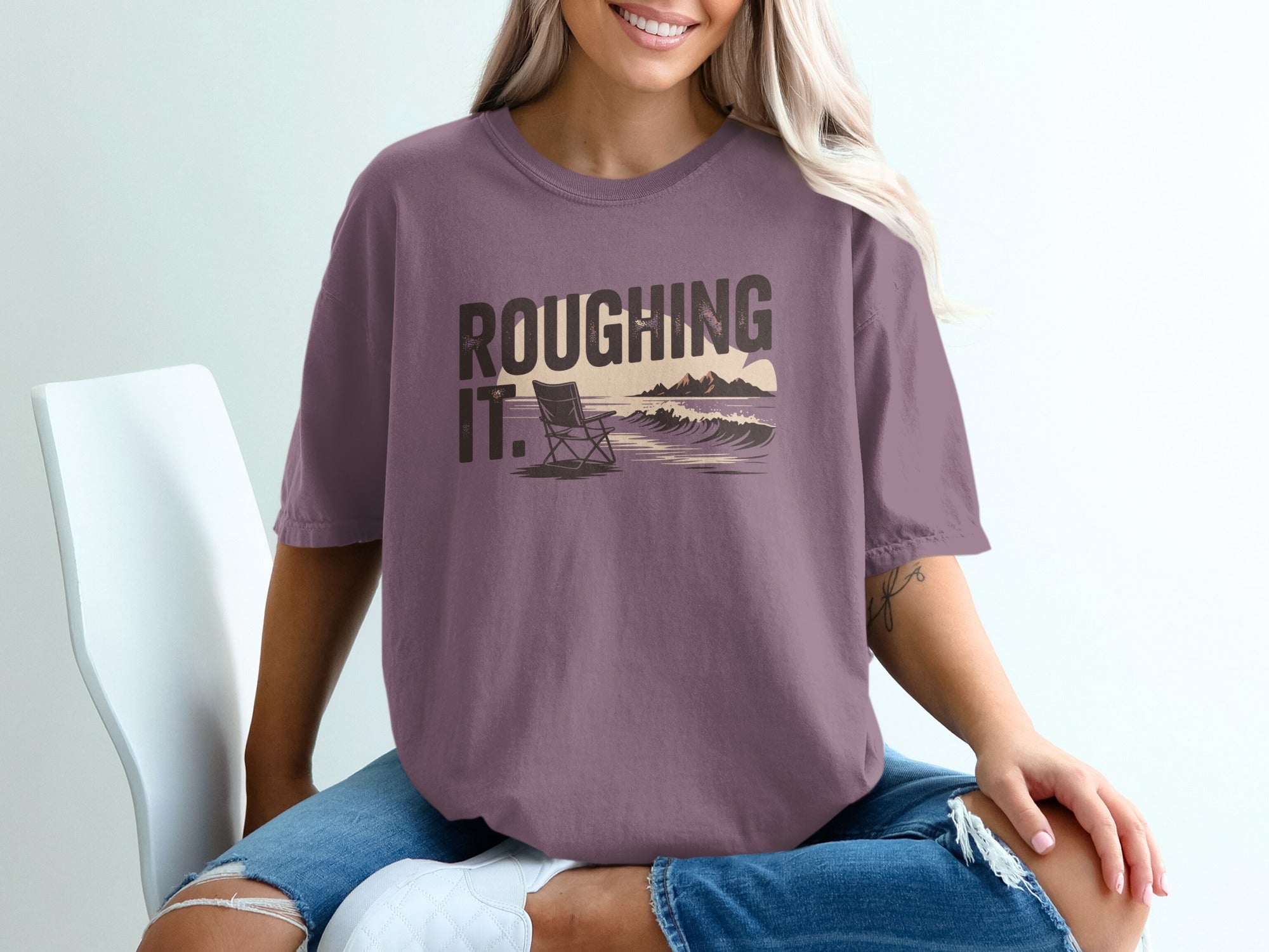 Purple t-shirt with "ROUGHING IT." text and a beach scene.