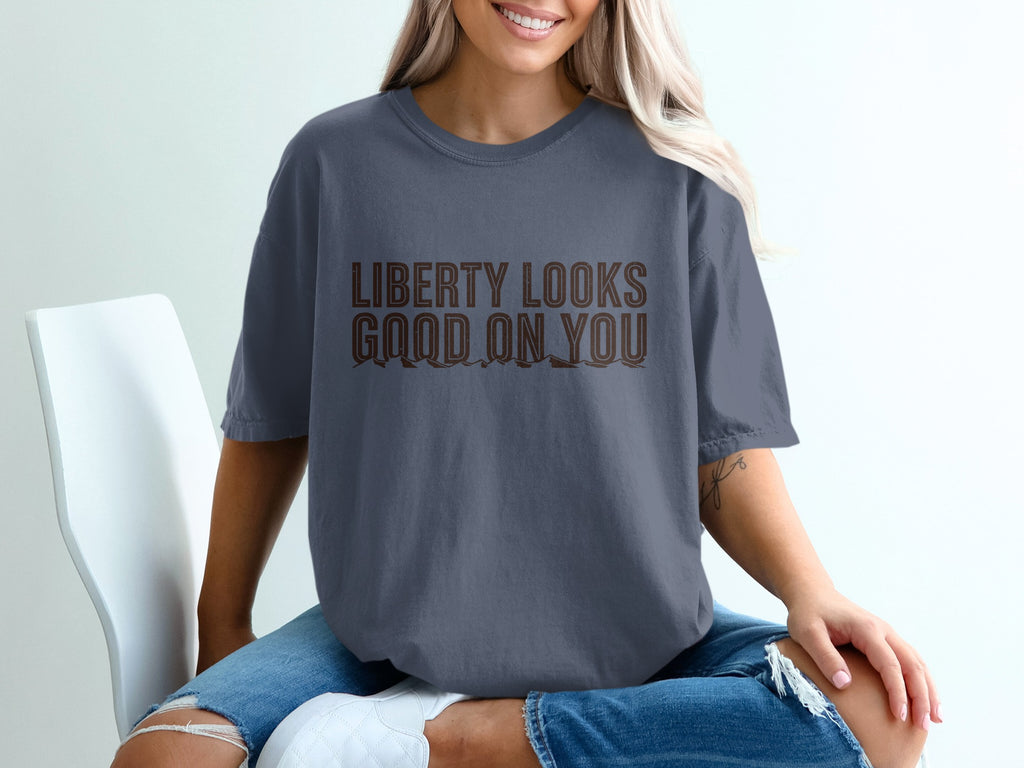 Woman in gray t-shirt with brown text reading "LIBERTY LOOKS GOOD ON YOU".