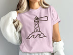 Pink t-shirt with a minimalist lighthouse graphic and wavy lines.