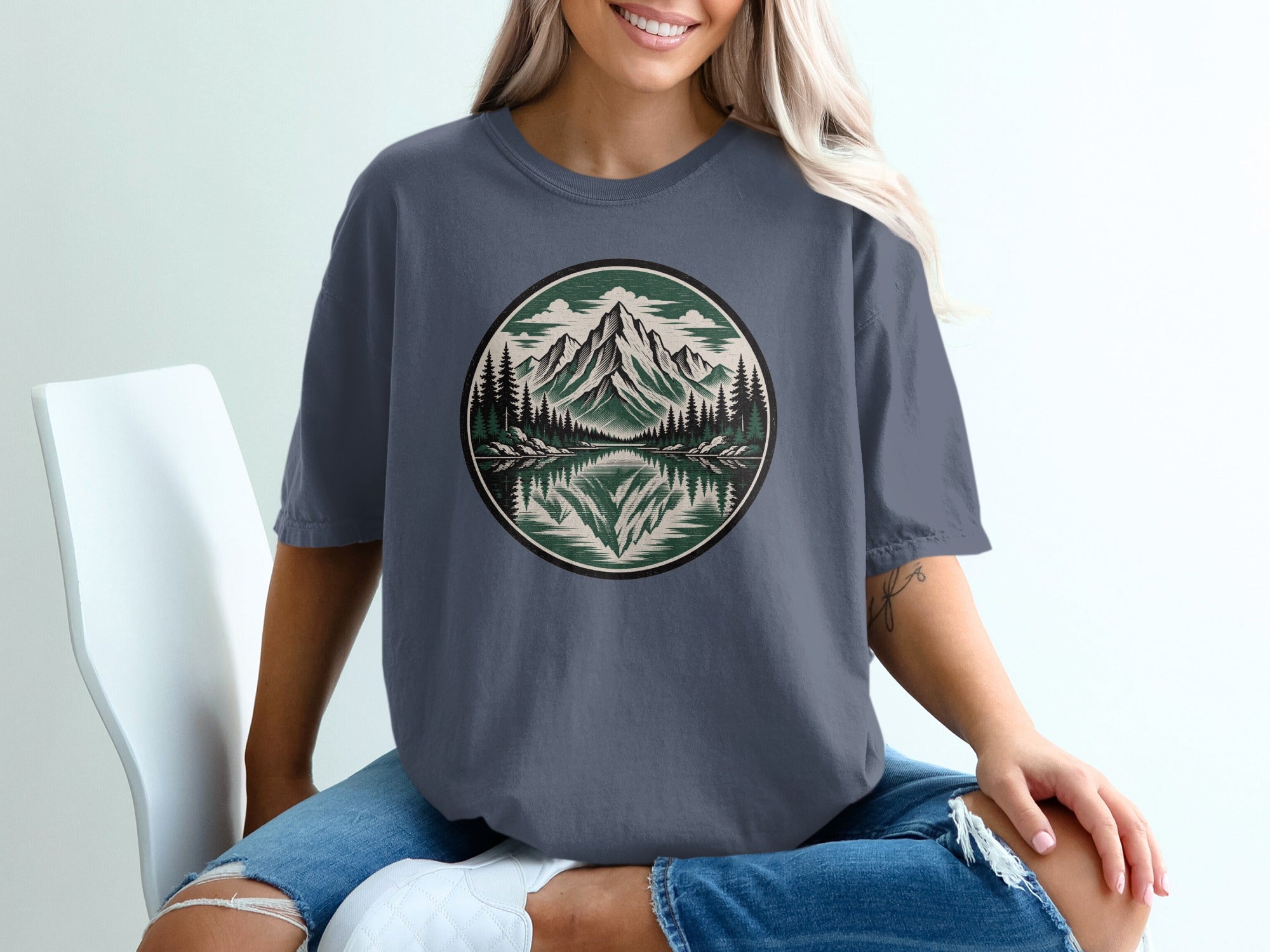 T-shirt with circular mountain, pine trees, and lake graphic.