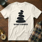 White t-shirt with stacked stones graphic and "BALANCE IS OVERRATED" text.