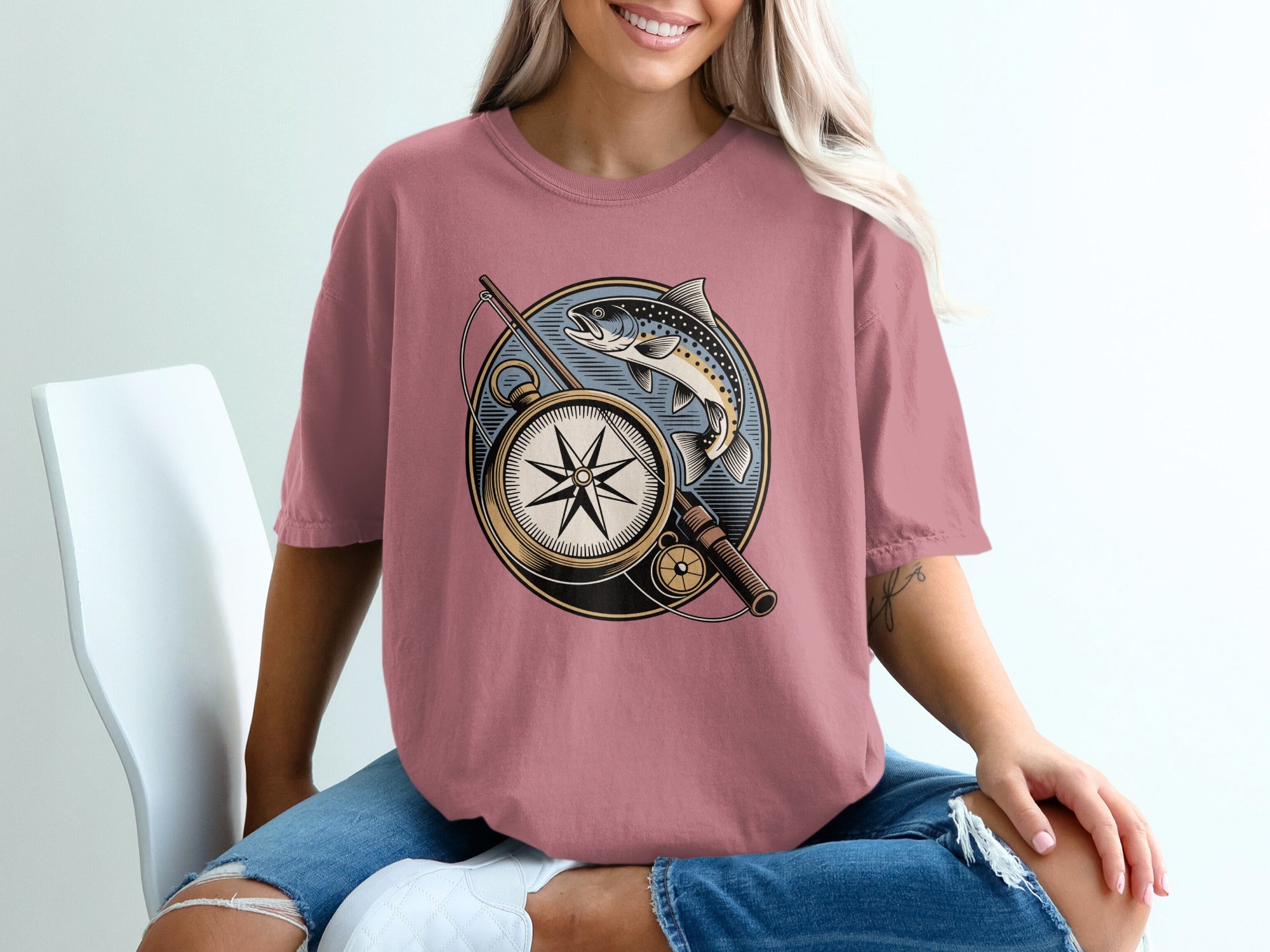 T-shirt graphic featuring a fish, compass, and fishing rod within a circular frame.