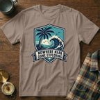 T-shirt with a shield design featuring a palm tree, wave, and the text "Nowhere Near Done Exploring."