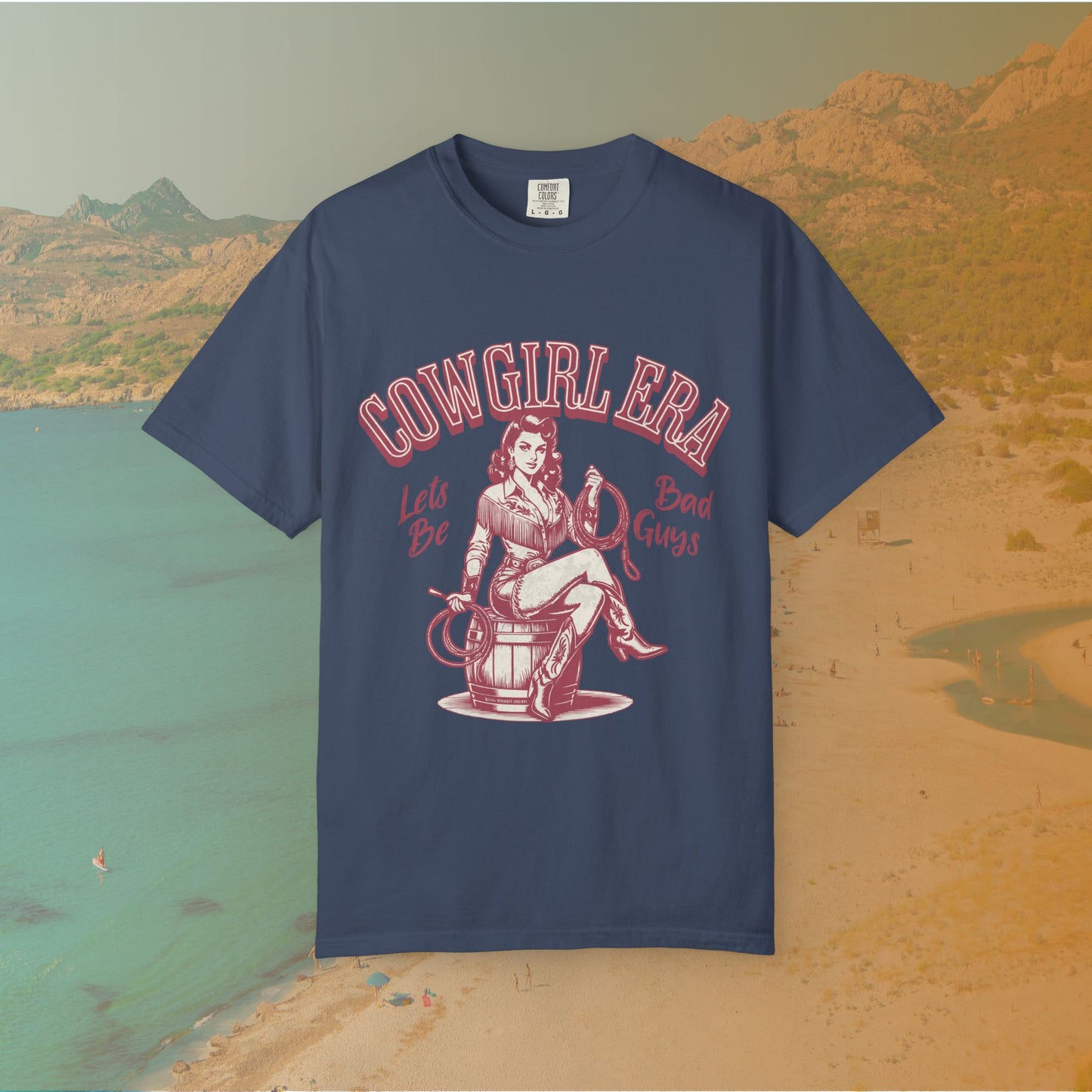Cowgirl Era pinup T-shirt with a vintage-style illustration of a sassy cowgirl sitting on a barrel holding a lasso. The graphic includes the text "COWGIRL ERA" and "Lets Be Bad Guys.
