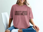 Rose t-shirt with black text "LIBERTY LOOKS GOOD ON YOU" and mountain graphic.
