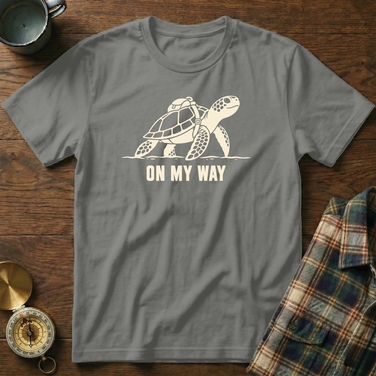 Grey t-shirt with a cream graphic of a sea turtle with a backpack and the text "ON MY WAY".