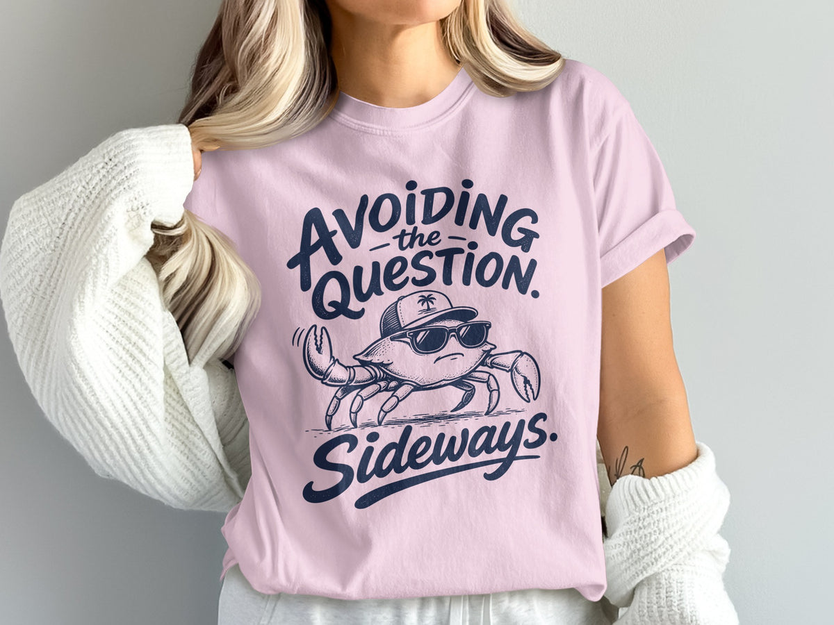 A light pink t-shirt with dark blue text that reads Avoiding the Question Sideways above a crab wearing sunglasses and a cap.