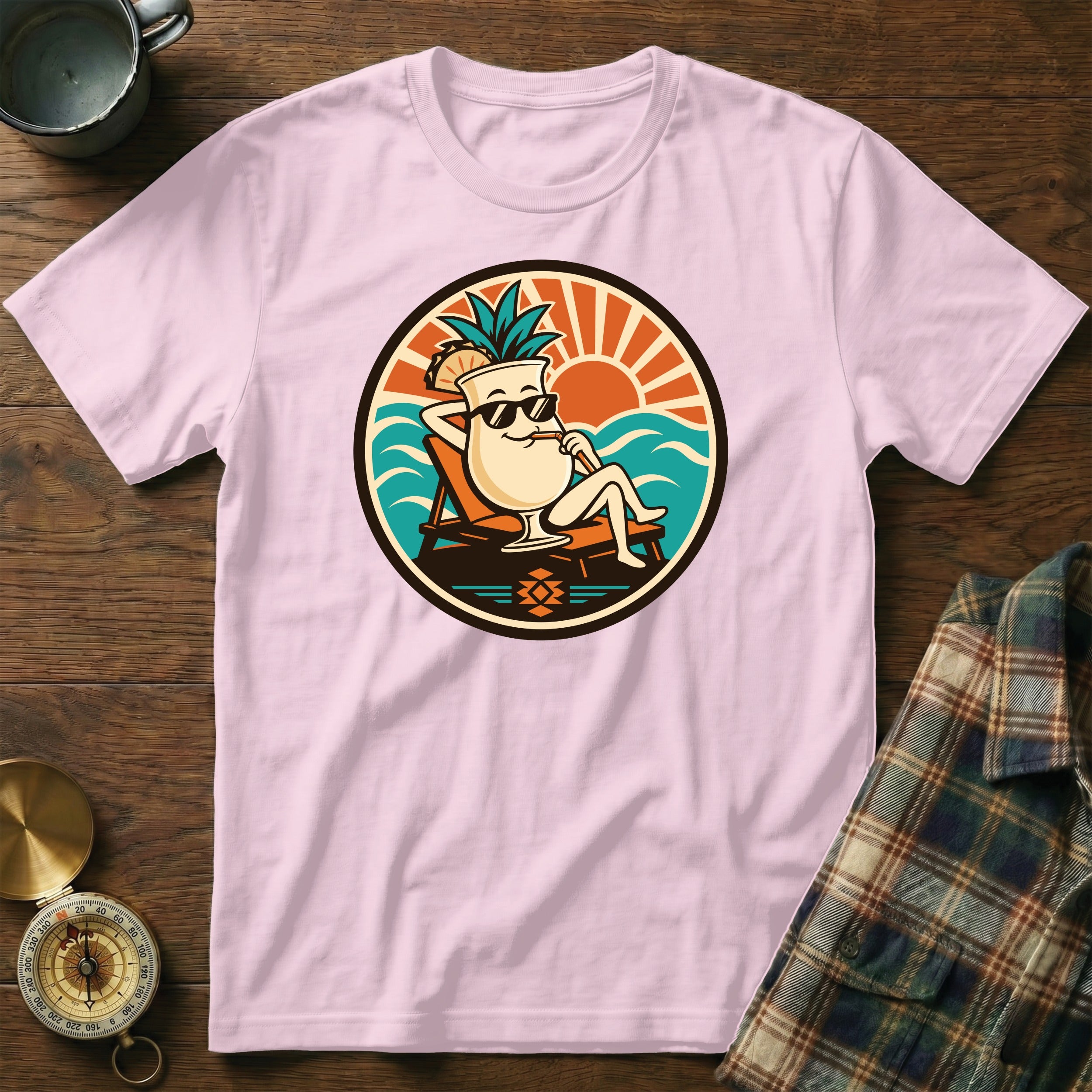 Pink t-shirt with a circular graphic of a smiling cocktail drink wearing sunglasses on a beach.
