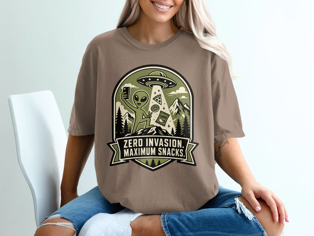 Alien with snacks under UFO with text "ZERO INVASION. MAXIMUM SNACKS."