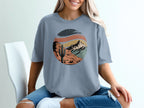 Circular desert landscape graphic with mountains, cactus, and tent on a t-shirt.