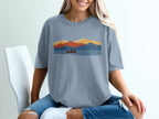 T-shirt with a graphic of a kayaker on a lake with layered mountains.