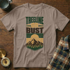 Brown t-shirt with graphic text "Treeline Or Bust" and mountain sunset design.