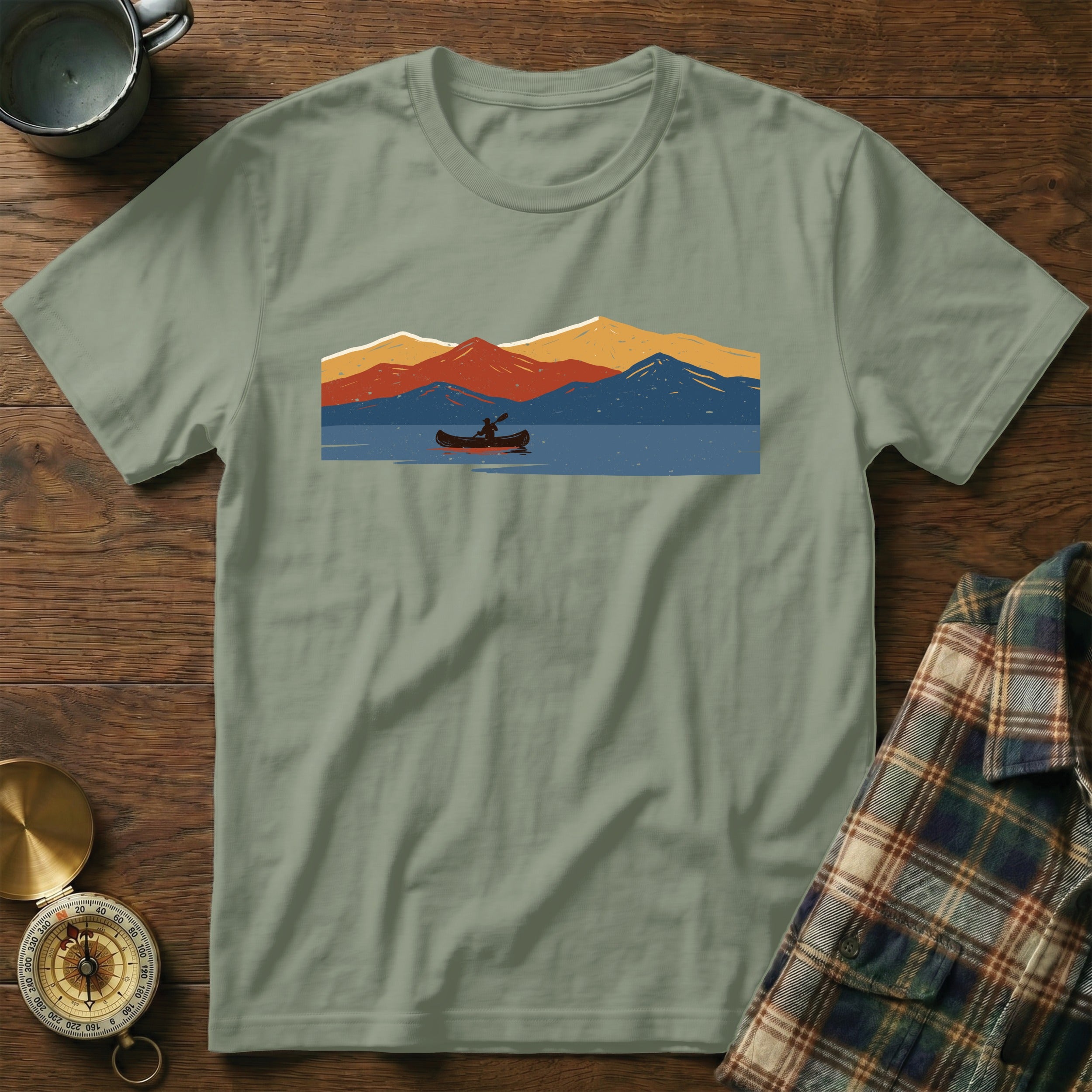 T-shirt with a graphic of a person in a canoe with mountains over a lake.