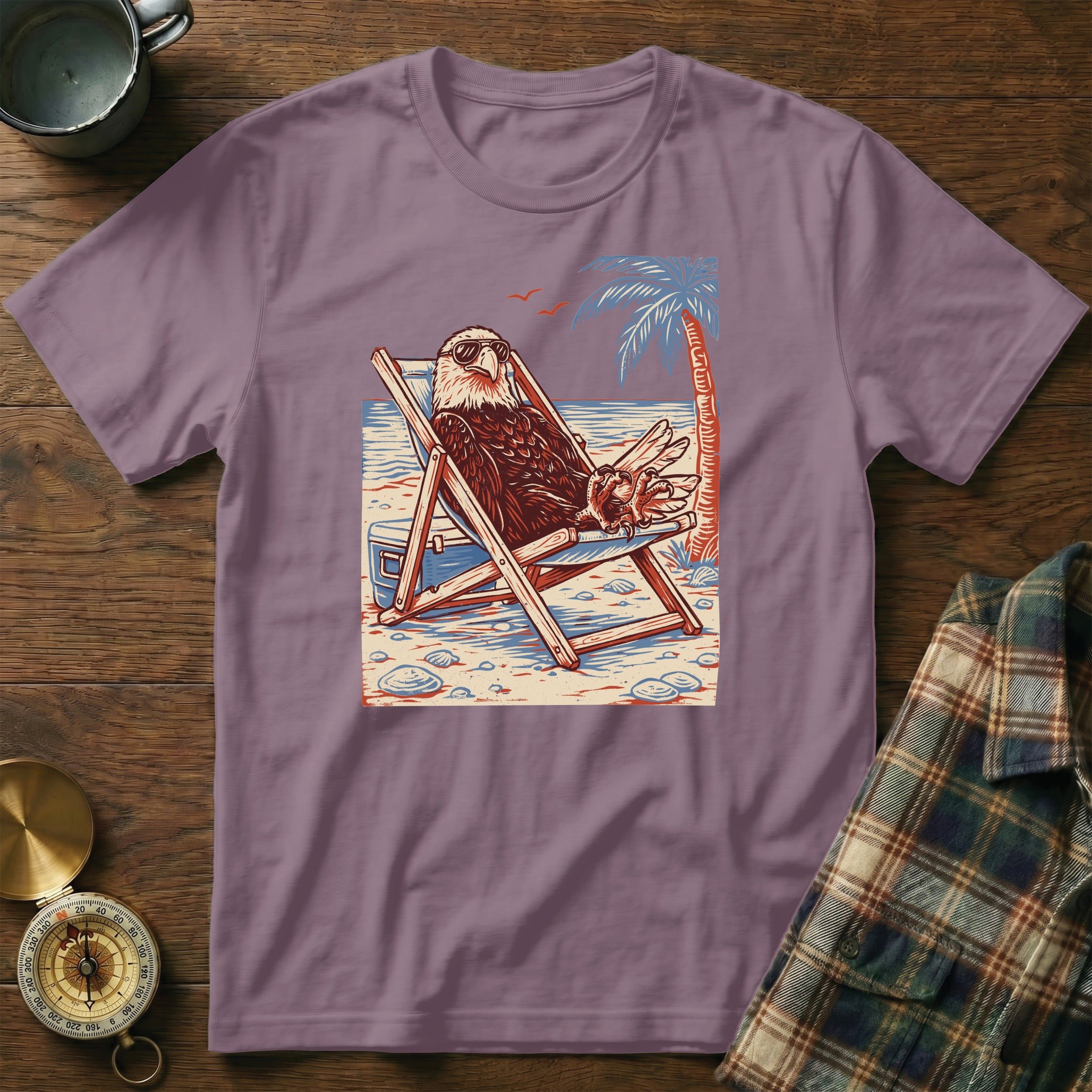 Bald eagle wearing sunglasses relaxes in a deck chair on a beach with a palm tree.
