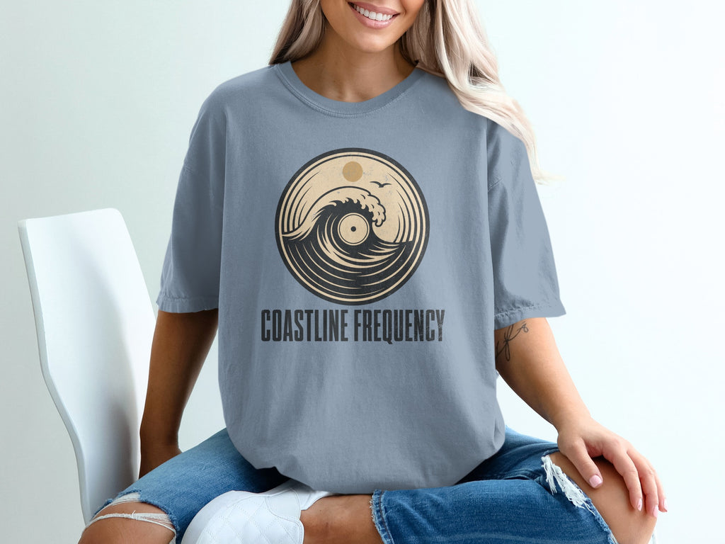 T-shirt with circular wave and sun graphic above "COASTLINE FREQUENCY" text.