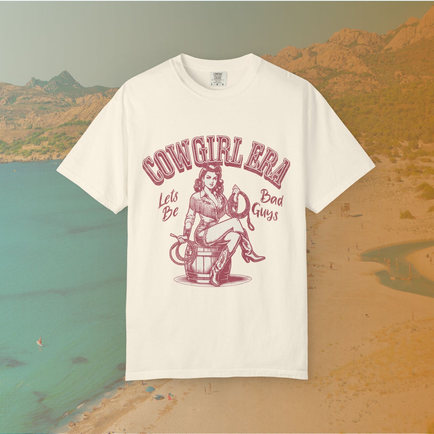 Cowgirl Era pinup T-shirt with a vintage-style illustration of a sassy cowgirl sitting on a barrel holding a lasso. The graphic includes the text "COWGIRL ERA" and "Lets Be Bad Guys.