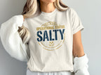 Cream t-shirt with "SALTY" in blue and gold nautical design.